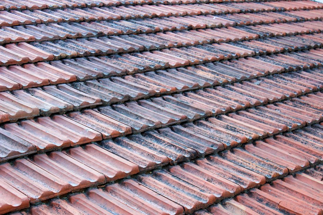 Weathered clay roof tiles with moss in the joints